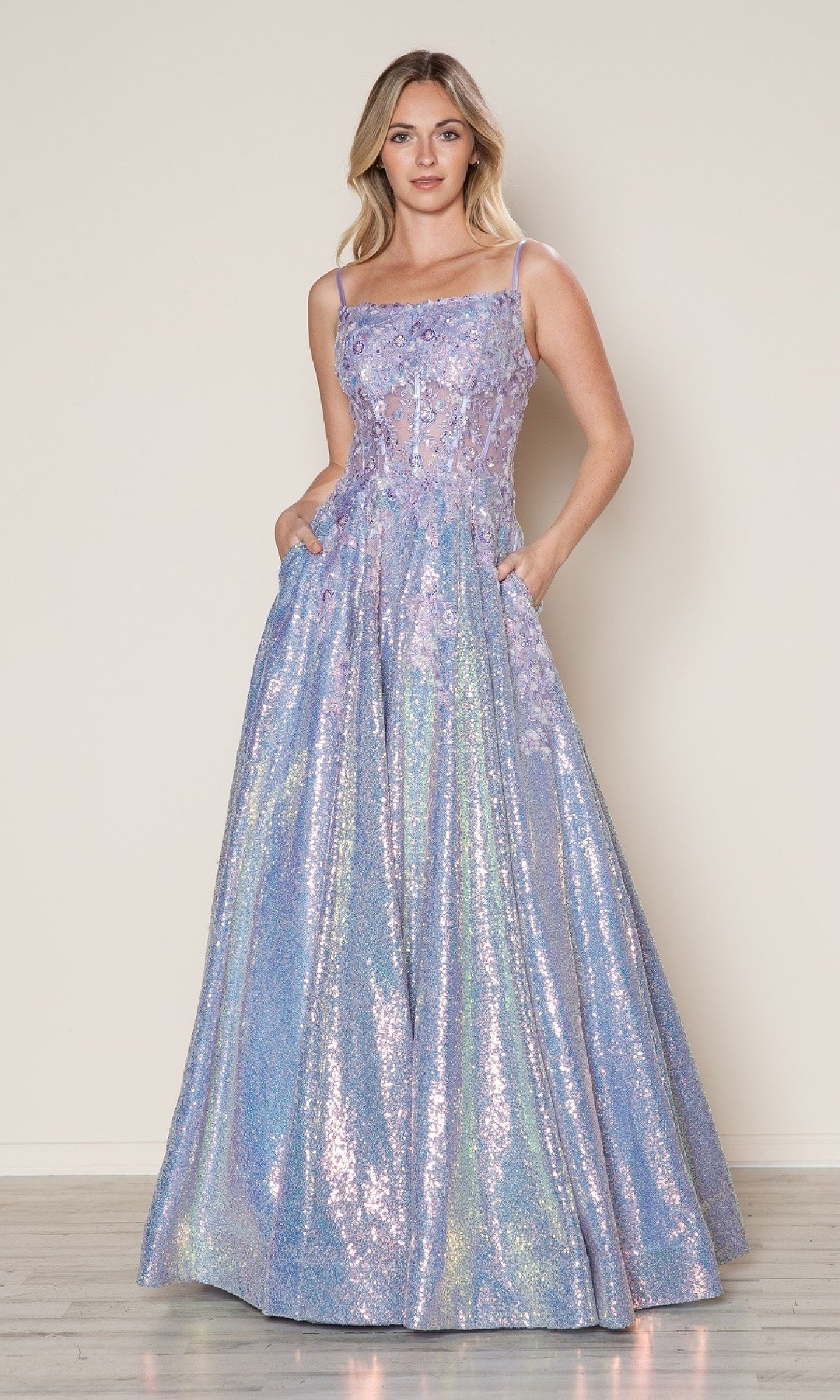 A woman wears the Poly USA 9554 Side-Pockets Long Sequin Prom Dress in iridescent lavender, featuring a sleeveless A-line design with a sheer bodice and pockets, standing against a plain background.